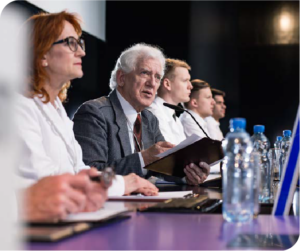 Photo of a group of professionals sitting at a table on a stage.