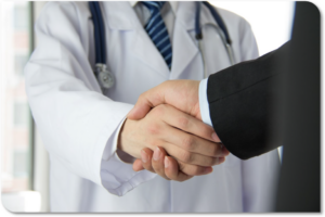 Photo showing a male doctor shaking hands with a man in a suit.