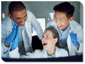 Three excited people huddled around a computer in a laboratory