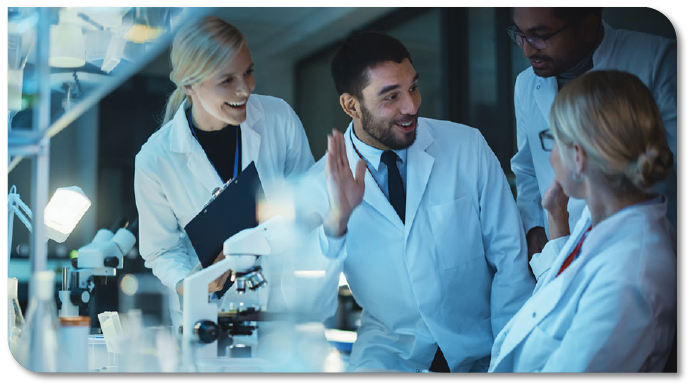 Group of happy scientists high fiving each other in a laboratory.