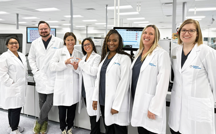 Group of lab workers posing in front of laboratory instrumentation